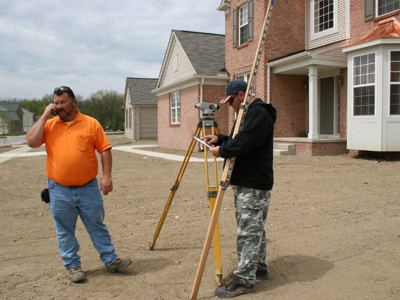 Surveyors performing an as-built survey on a newly constructed home to verify building location and site measurements